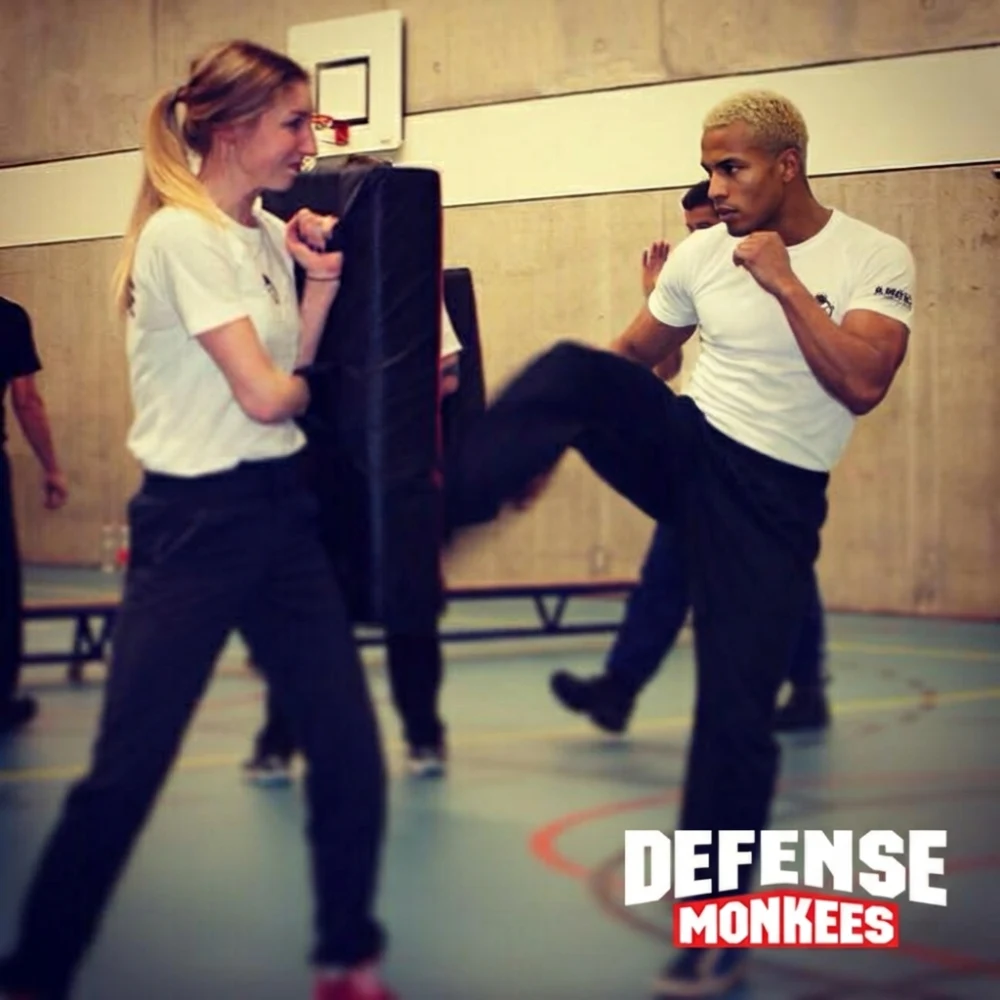Krav Maga training bij DefenseMonkees waarbij een cursist een traptechniek oefent op een stootkussen tijdens een realistische zelfverdedigingsles in de sportschool.